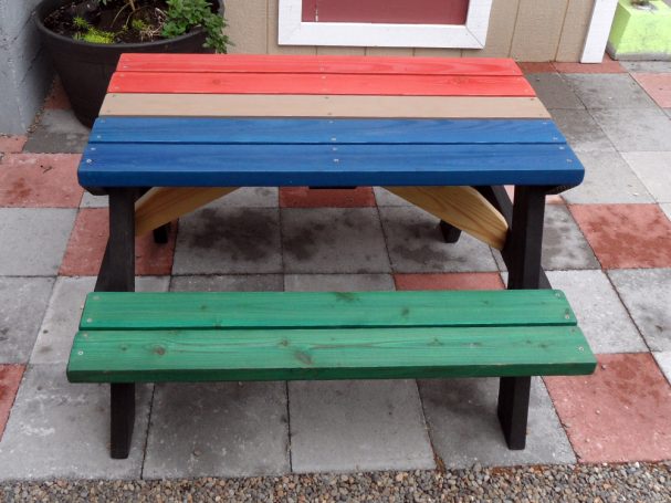 Multicolored Commercial quality Eco-friendly Outdoor Kids Attached Bench Picnic Table from the side on a sidewalk.