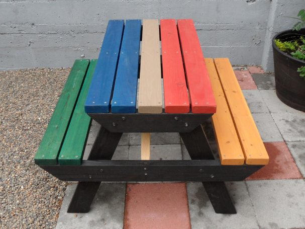 Multicolored Commercial quality Eco-friendly Outdoor Kids Attached Bench Picnic Table from the front on a sidewalk.