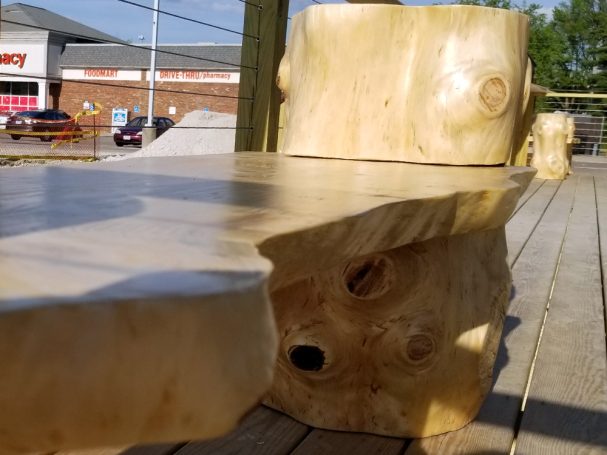 Close up of Handcrafted Pine Log Live Edge Slab Bench on the patio at High Grain Brewery slanted to the right.