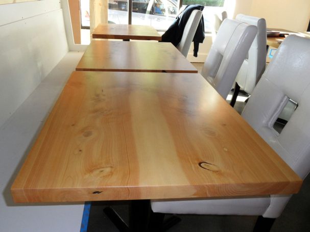 Three dining tables with commercial quality Handcrafted Juniper Table Tops in a row inside a restaurant bar.