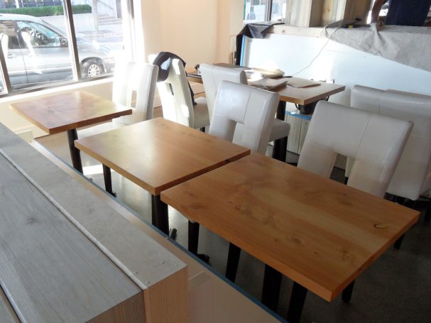 Three dining tables with commercial quality Handcrafted Juniper Table Tops slanted to the left inside a restaurant bar.