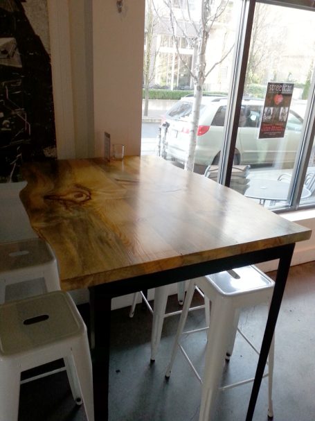 Close up of a commercial quality Blue Pine Live Edge Slab Table Top dining table slanted to the left at restaurant bar.