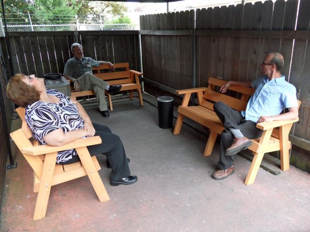 Reddish orange 5' Commercial quality eco-friendly Outdoor Park Benches slanted to the left at a restaurant bar.